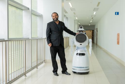 A medical doctor poses with a health services robot