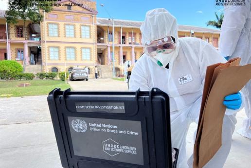 A crime scene investigator wearing protective personal equipment looks inside a crime scene investigation kit provided by UNODC during training at the Police Academy at the Police Barracks in St. James.