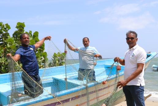 Fishermen pose while holding up a fishing net