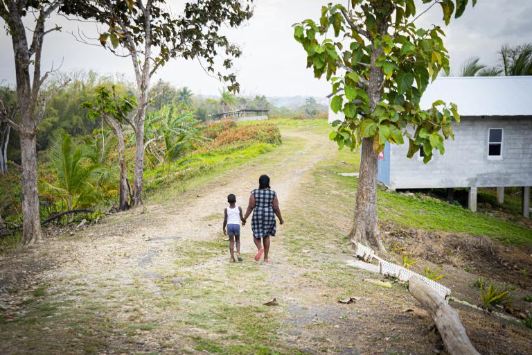 A mother and child walk down a rural road